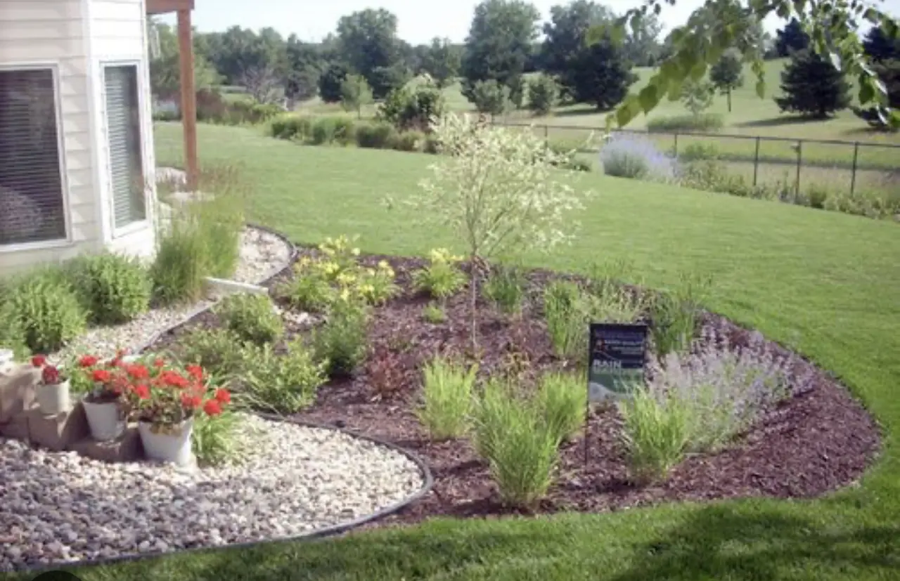 Curved mulch and river rock bed with flowers and ornamental grasses