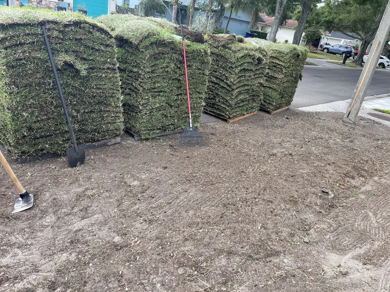 Stacked sod rolls in a bare, prepped yard